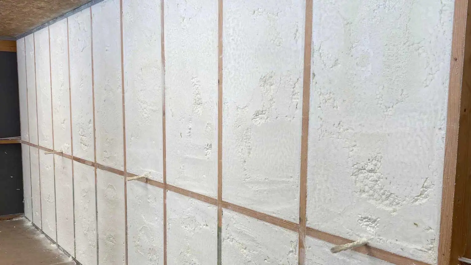3e37523c 40de 44c9 9468 e2b18919a447 1 Unfinished wall with white insulation panels between vertical wooden studs in a construction space